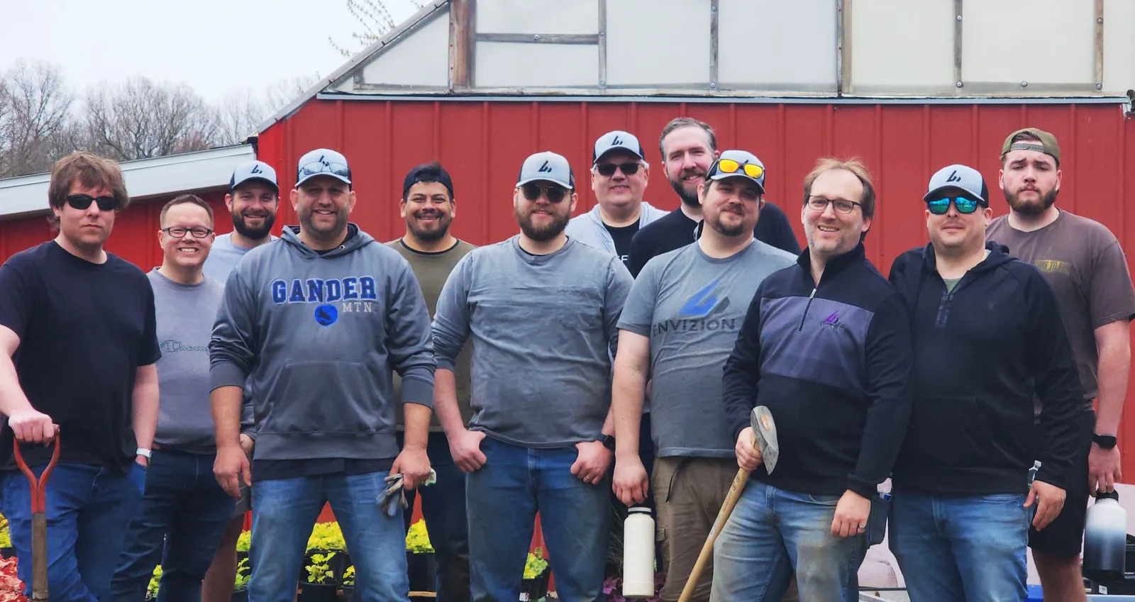 Envizion IT team holding gardening tools at New Growth Project.